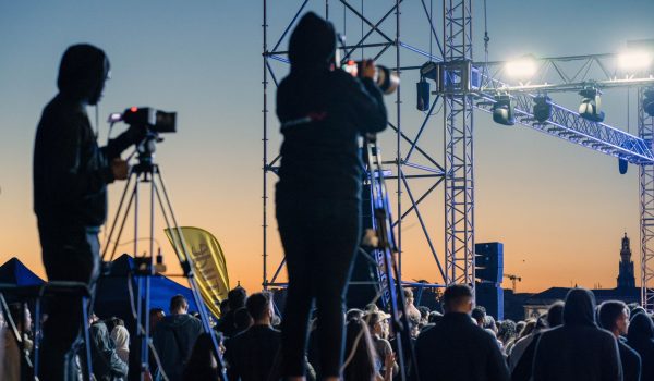 Cameramen on platforms capture the excitement of a live event at sunset.
